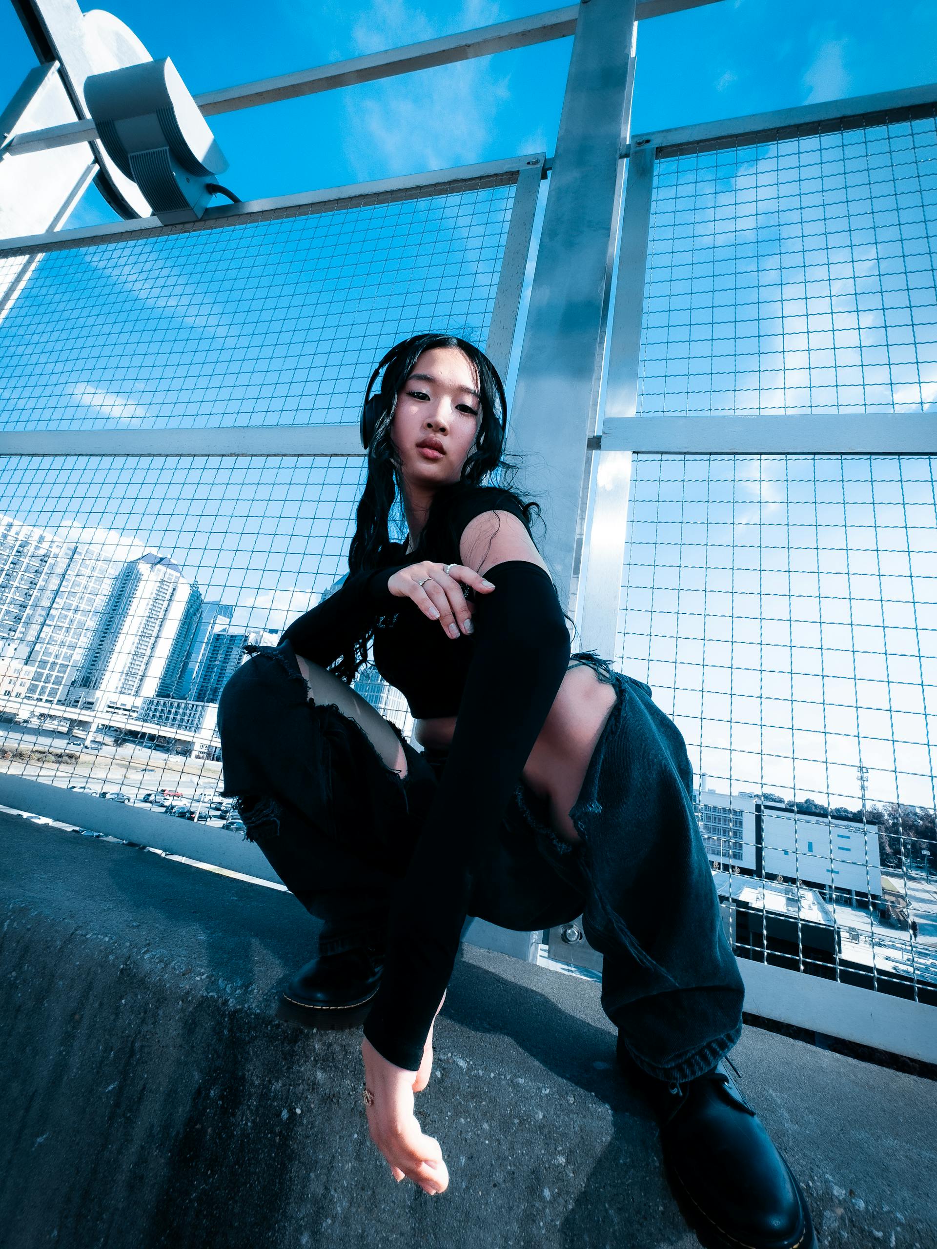 Low angle view of model posing in urban Atlanta setting under blue sky.